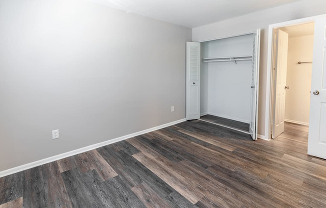 an empty room with hard wood flooring and a closet