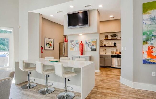 A modern kitchen with white bar stools and a white counter.