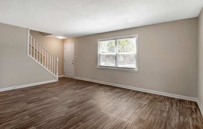 an empty living room with a staircase in the background