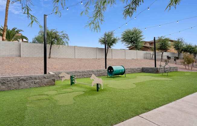 A small green lawn with a swing set and a green barrel. at The Laurel Apartments, Chandler