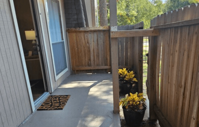 A wooden deck with a mat on the floor and a potted plant on the side.