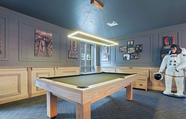 A room with a pool table and a person in an astronaut suit.