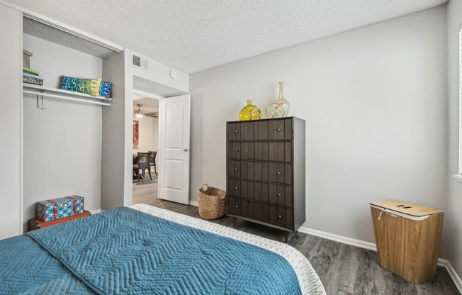 a bedroom with a blue bed and a wooden dresser