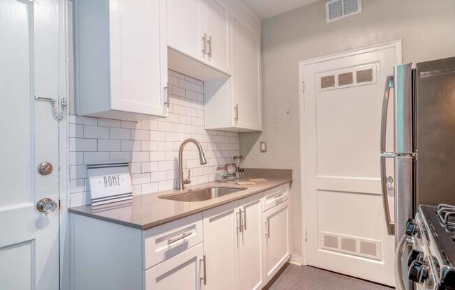 a kitchen with white cabinets and stainless steel appliances