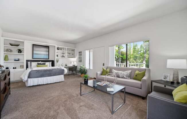 a living room with a couch coffee table and a bed in the background