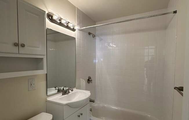A white bathroom with a toilet, sink, and bathtub.