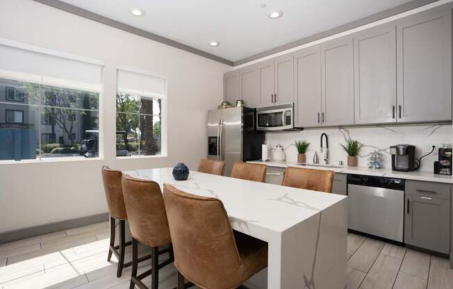 A kitchen with a white counter and brown chairs.