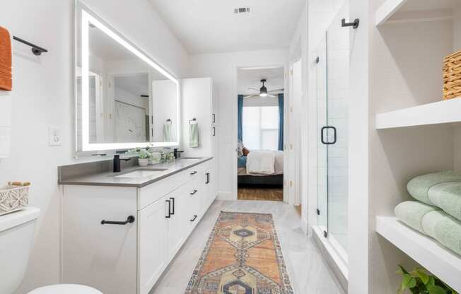 a white bathroom with a large mirror and a rug