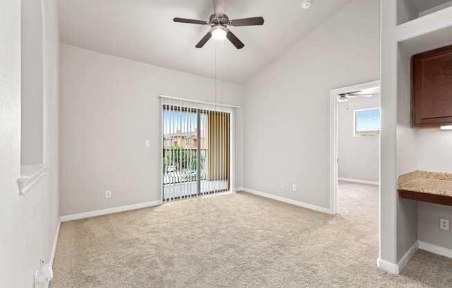 an empty living room with a ceiling fan and a sliding glass door