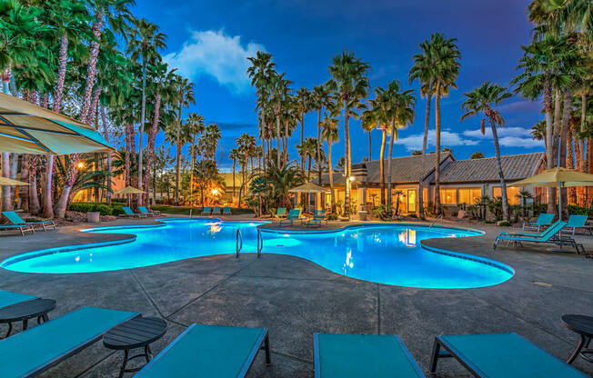 A pool surrounded by palm trees at dusk.