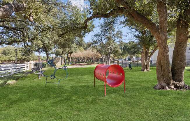 A playground with a red slide and a blue swing set.