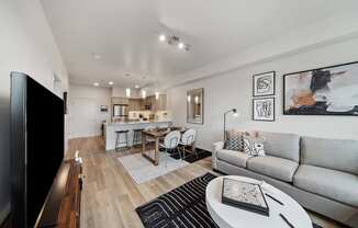 A modern living room with a grey couch, a wooden coffee table, and a flat screen TV.