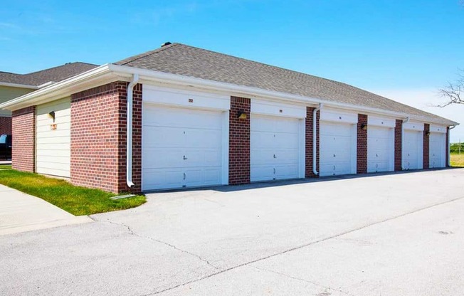 a garage with three white garage doors on the side of a house