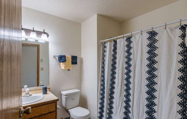 a bathroom with a shower and a toilet and a sink. Fargo, ND Crescent Park Apartments