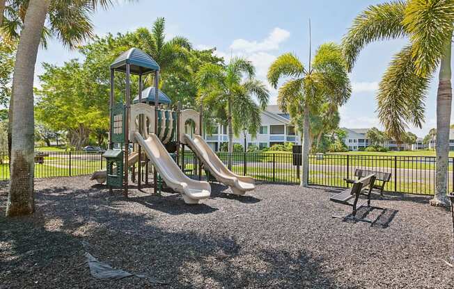 playground with slides and picnic tables in front of a house at The Villages of Banyan Grove, Boynton Beach