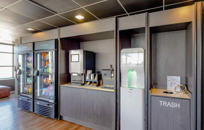 A room with a trash bin and a fridge.