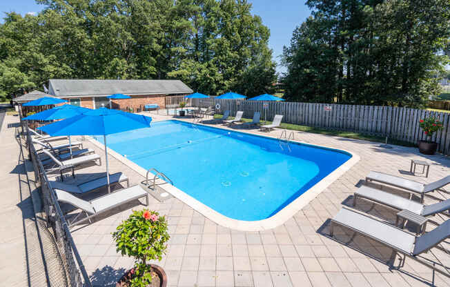 a swimming pool with chairs and umbrellas and a resort style pool