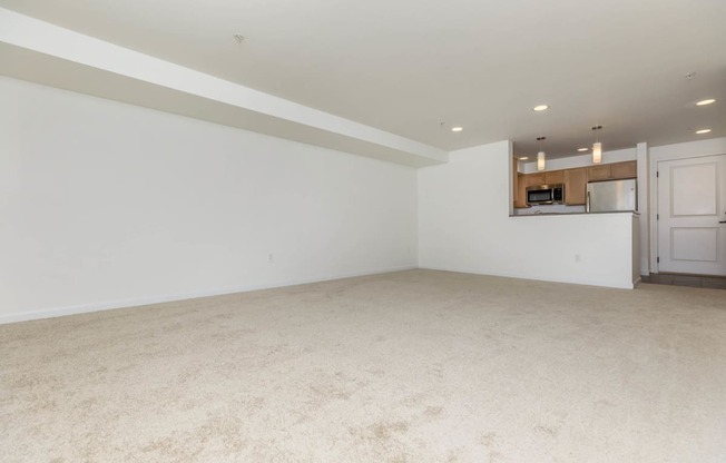 an empty living room and kitchen with white walls and carpet  at Delano, Redmond, WA