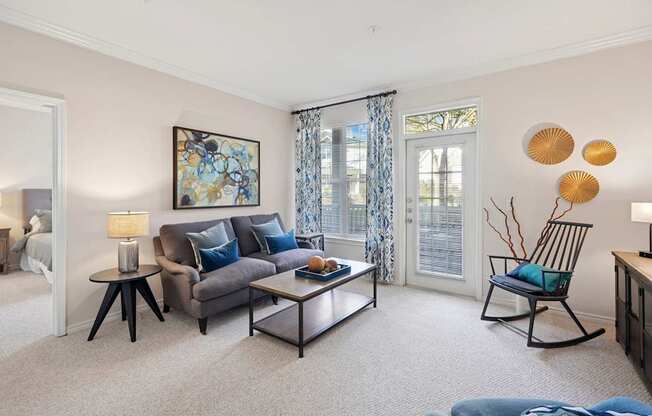 A living room with a grey couch, a coffee table, and a painting on the wall.