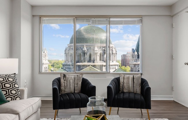 a living room with two black chairs and a large window with a view of the dome of