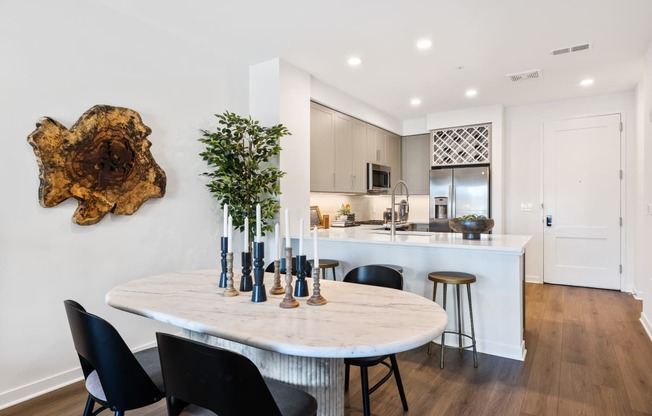 an open kitchen and dining area with a marble table and black chairs