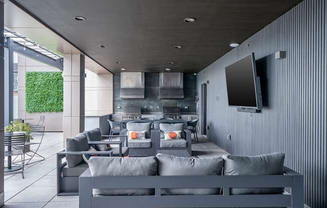 A modern living room with grey furniture and a flat screen TV mounted on the wall.