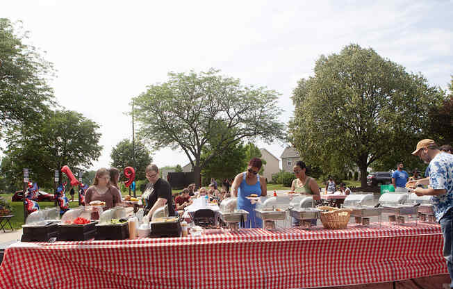 people preparing food at a picnic table in a park