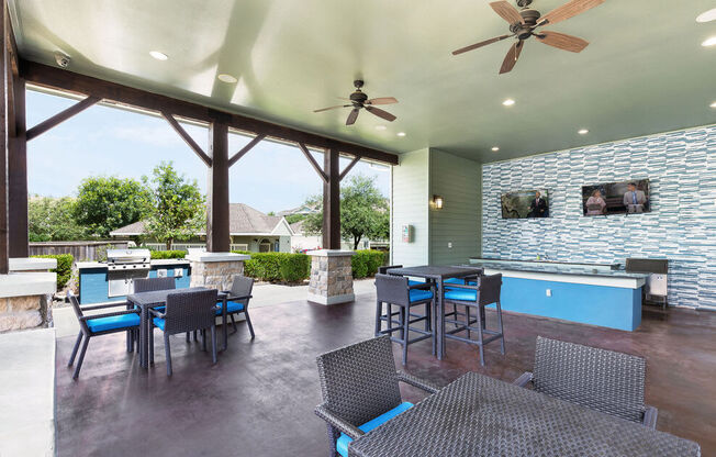 a patio with a fireplace and a bar with chairs and tables
