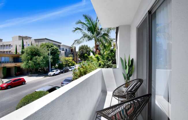 a balcony with two chairs and a plant