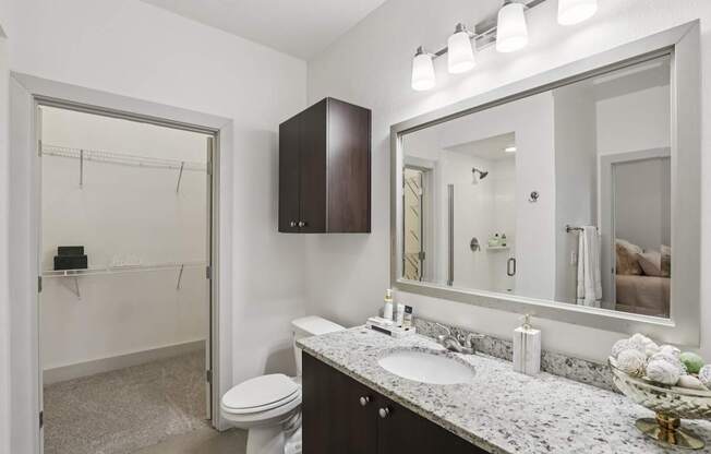 A bathroom with a toilet, sink, and mirror.