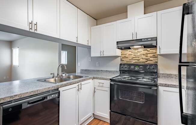 a kitchen with white cabinets and black appliances