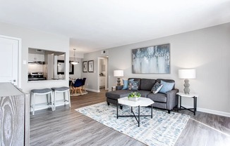 A living room with a grey couch, a white coffee table, and a painting on the wall.