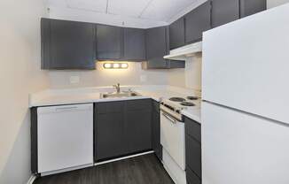 A kitchen with black cabinets and white appliances.