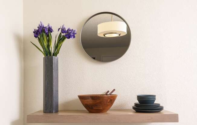 a shelf with a mirror and a vase with flowers on it