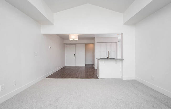 A large, empty living and dining room with a carpeted floor at The Crossings Apartments, Grand Rapids, MI, 49508