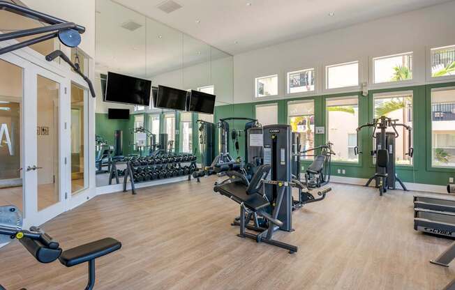A gym with a variety of equipment including treadmills, weights, and exercise machines.