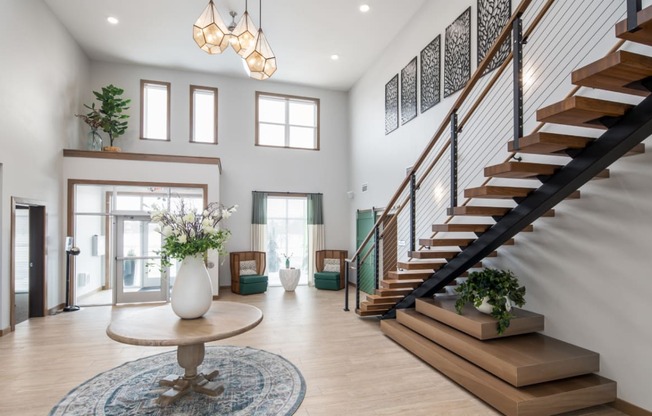 A spacious interior with a staircase, a table with a vase, and a rug.