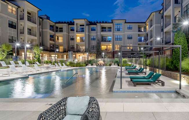 an apartment swimming pool with lounge chairs at night at The Hendrix, Georgia