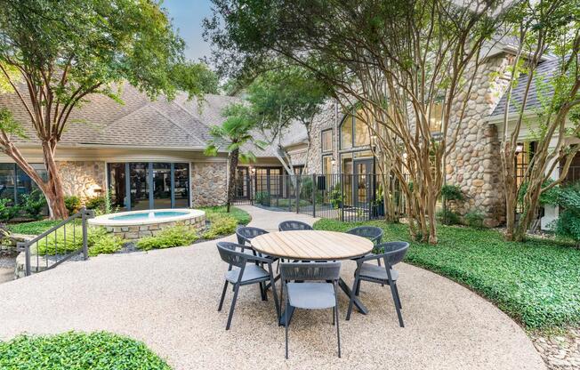Shaded by mature trees and surrounded by stonework charm, this courtyard offers a welcoming spot to relax or catch up with neighbors.
