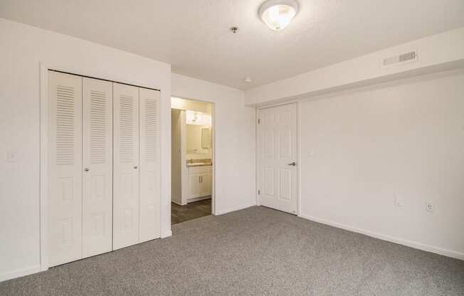 an empty bedroom with spacious closets and a carpeted floor at Canal 2 Apartments, Lansing, Michigan