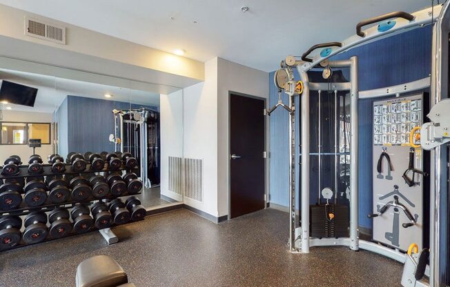 Fitness Center with hard rubber flooring, strength cable machine and dumbbell rack with mirror behind
