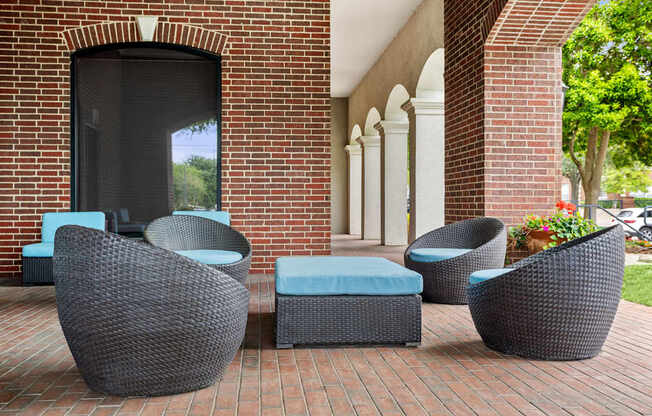 A set of outdoor furniture including chairs and ottoman in front of a building.