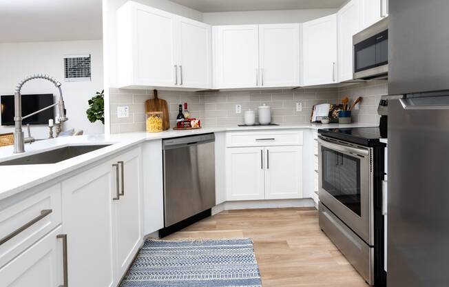 a white kitchen with stainless steel appliances and white cabinets