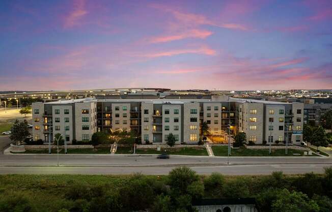 A large apartment complex is shown with a beautiful sunset in the background.
