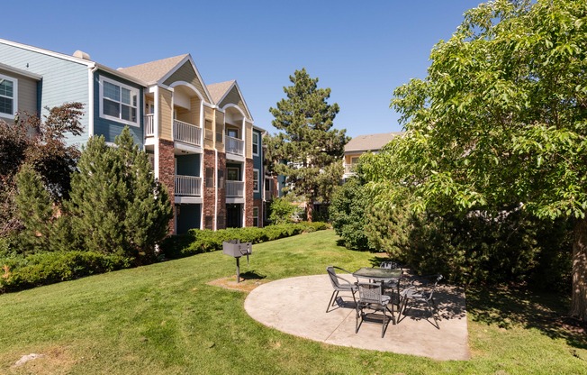 a patio with a table and chairs in front of an apartment building