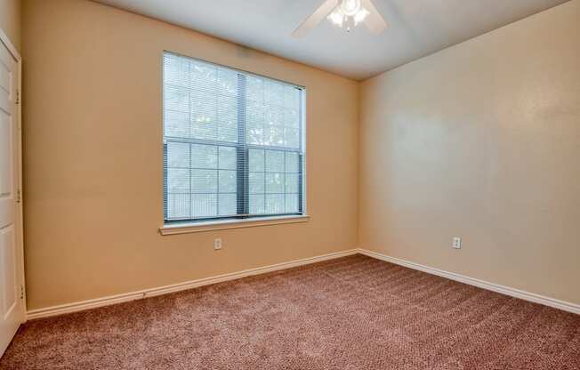 a bedroom with a ceiling fan and a large window