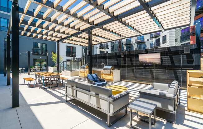Outdoor community space with grills, sofas, and TV