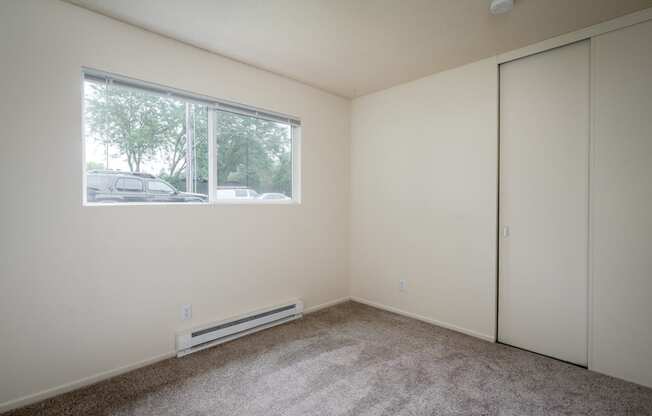 a bedroom with a large window and white walls