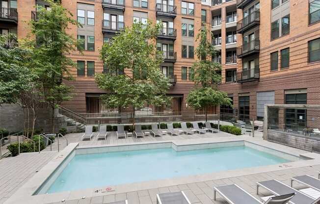 a swimming pool with chairs in front of a building