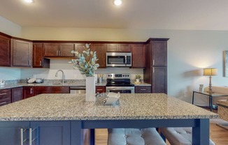 a kitchen with a large island and a living room in the background